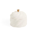 A white ceramic lidded container with a sculpted, ribbed surface and a small metallic gold knob on top, shown against a plain white background.