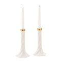 A pair of white taper candle holders with a twisted flared base and a thin gold band near the top, each holding a white taper candle, shown on a plain white background.