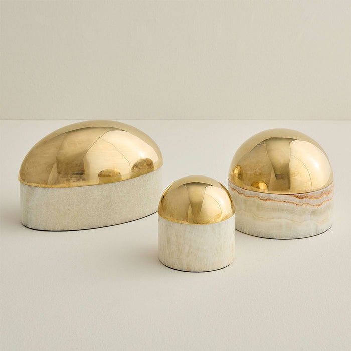 Three decorative items with gold and white finishes on a light background