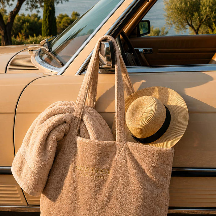 Sac de plage beige Gemology accroché à une voiture cabriolet avec chapeau de paille, ambiance estivale premium
