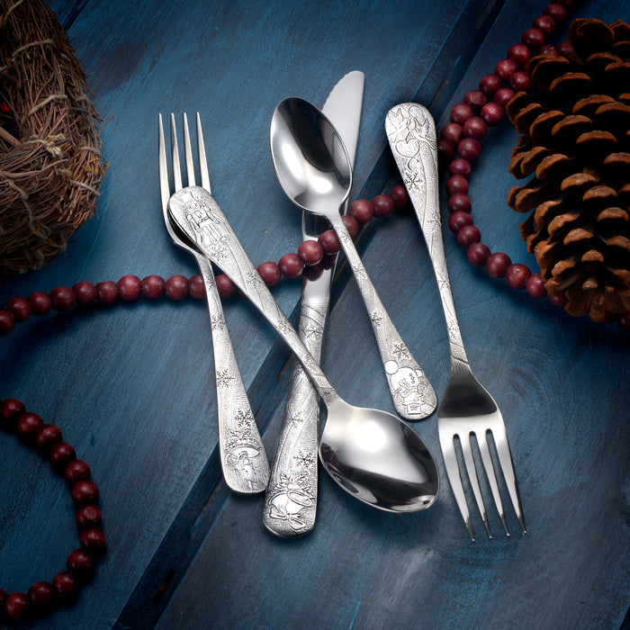 Angled overhead of Holidays flatware: engraved silver forks and spoons on blue wood with pinecone and red bead garland