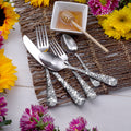 Angled view of Honey Bee 45-piece set flatware showing honeycomb bee-patterned handles on woven placemat with honey dipper