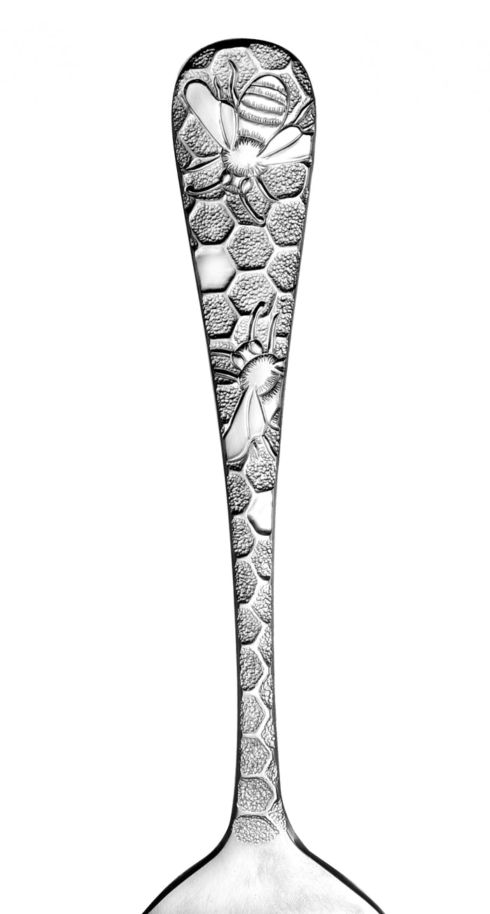 Close-up of a spoon handle featuring honeycomb and bee designs.