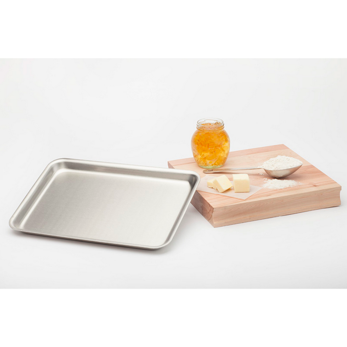 Rectangular metal jelly roll pan next to a wooden cutting board with a jar of orange marmalade, butter slices, and a bowl of flour.