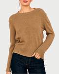 A woman wears the JUMPER1234 Distressed Cashmere Crew Sandstone, a relaxed fit knit sweater with distressed edges and long sleeves, styled with dark blue jeans against a plain background.