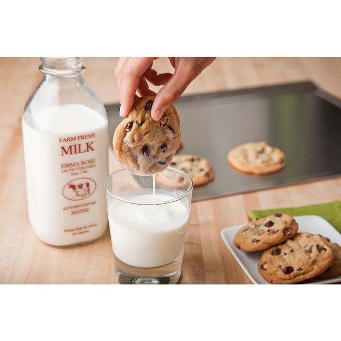 Angled view of Large Cookie Sheet showing rolled rim and steel surface with cookies and a hand dunking a cookie into milk