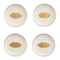 Four round white plates arranged in a 2x2 grid on a white background, each with a thin gold rim and a gold lips motif centered on the plate.