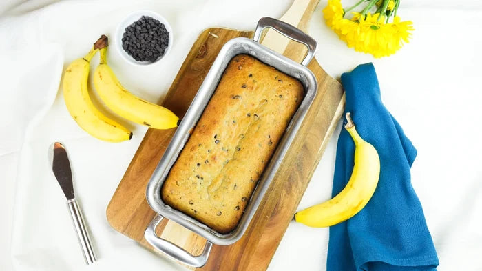Overhead view of Loaf Pan with Handles showing stainless steel finish holding banana bread on a wooden board with a blue napkin