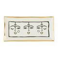 Rectangular ceramic tray with abstract face design on a white background