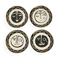 Four decorative plates with face designs on a white background
