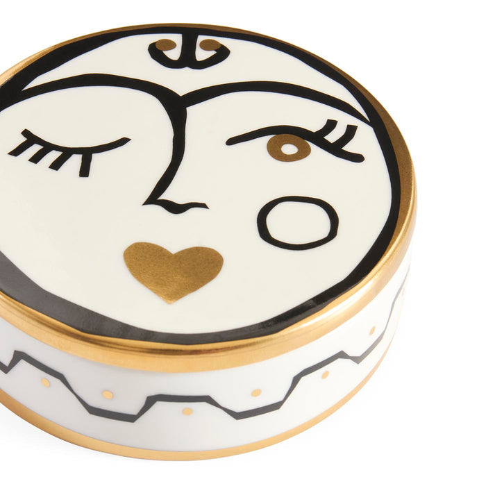 Decorative ceramic face with gold accents on a white background