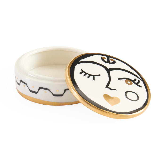Decorative ceramic container with face design on lid and body, on a white background