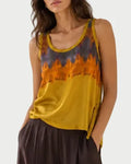 Woman wearing a sleeveless top with a tie-dye pattern and wide-leg pants against a white background