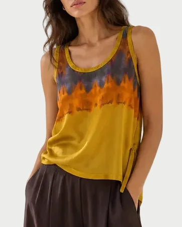 Woman wearing a sleeveless top with a tie-dye pattern and wide-leg pants against a white background