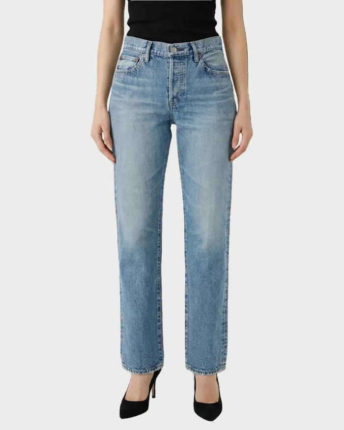 A person wearing Moussy Leyden Straight Jeans by Moussy and black heels, shown from waist to feet, stands against a white backdrop.