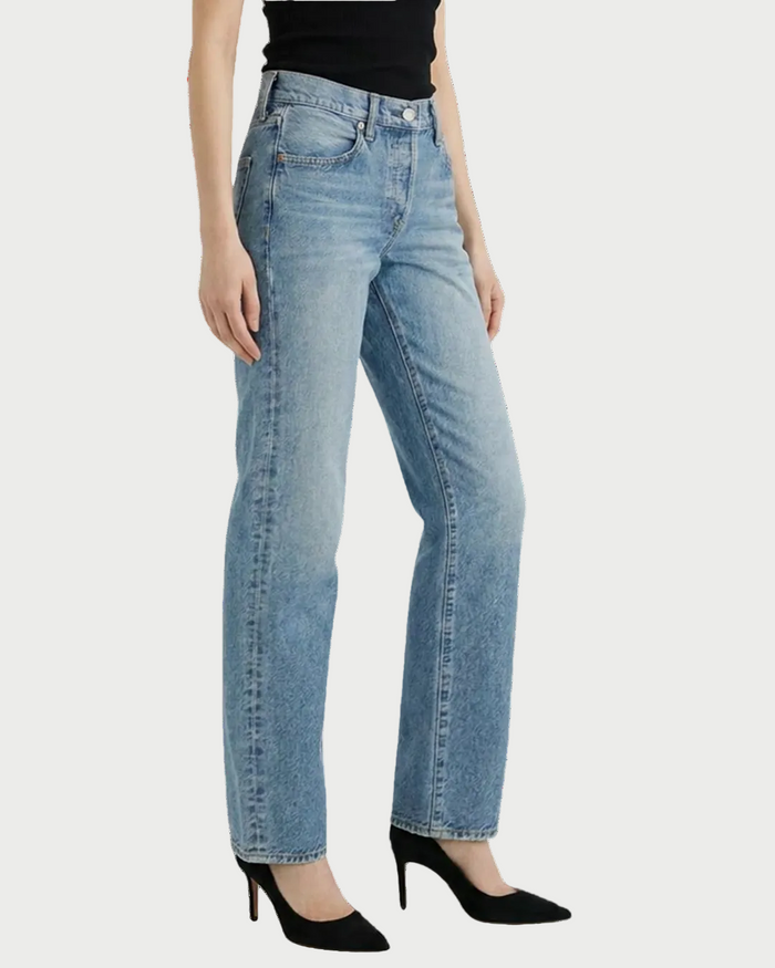 A person wearing Moussy Leyden Straight Jeans by Moussy, a black sleeveless top, and black pointed-toe heels stands against a plain white background.