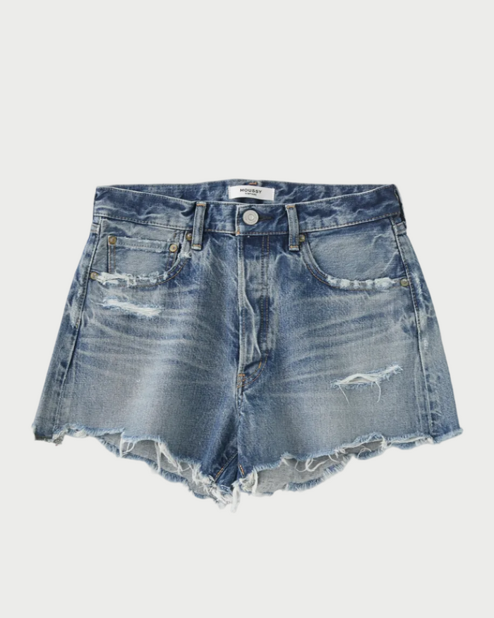 A pair of blue Moussy Packard Shorts by Moussy with distressed details, frayed hems, front pockets, belt loops, and a button fly closure. The 100% cotton fabric features several worn and torn areas, giving them a rugged, vintage look. The shorts are laid flat against a plain white background.