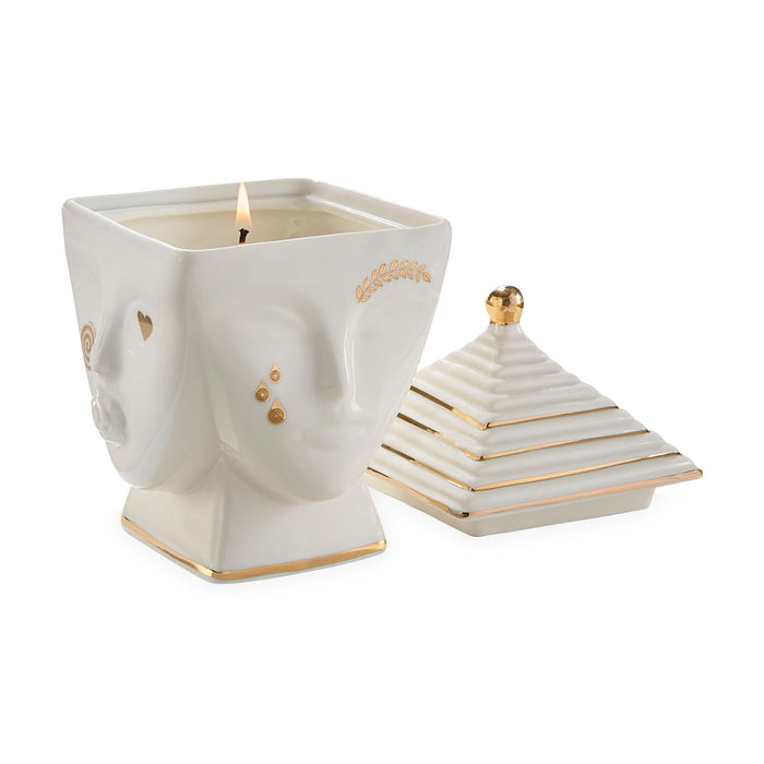 Decorative candle in a face-shaped holder with a matching pyramid-shaped lid on a white background