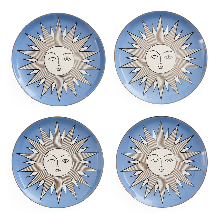 Four round ceramic plates arranged in a 2x2 grid, each featuring a light blue background with a stylized sun face design in white and gray.