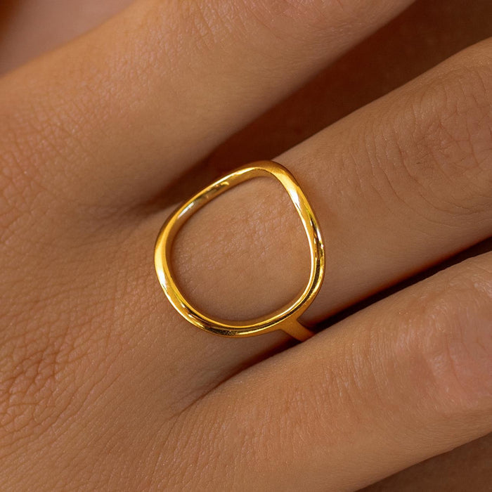 A gold-colored open circle ring with a simple, elegant design displayed on a person's finger.