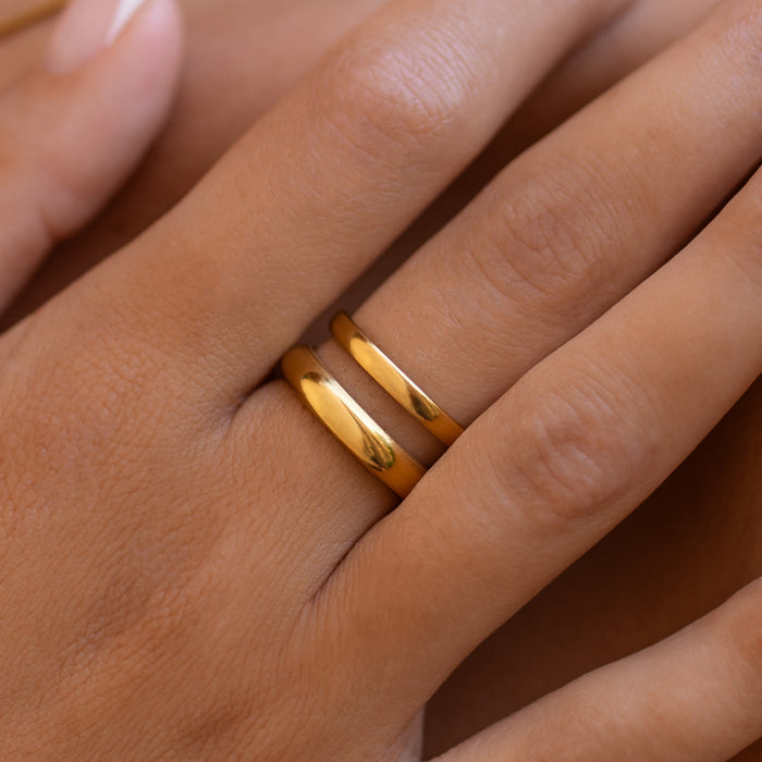 smooth gold double layer ring on a person's finger with a neutral background