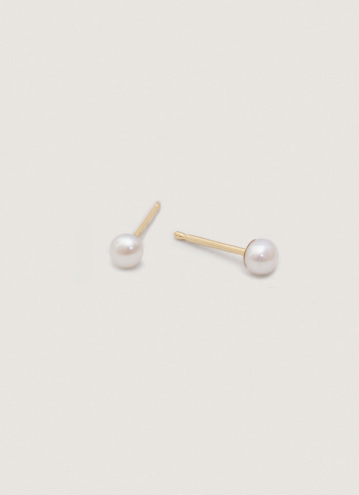 Angled view of a pair of Kinn 14k Gold Pearl Stud Earrings