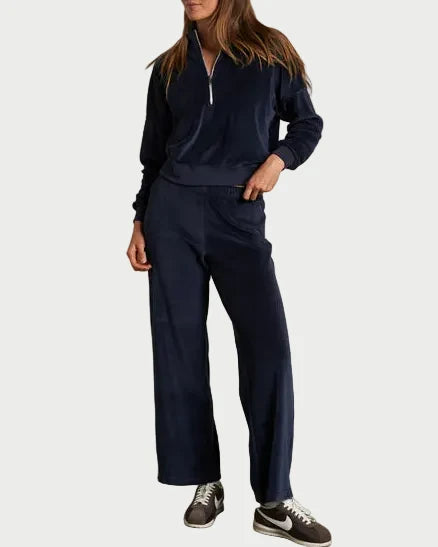 Person wearing a navy tracksuit against a plain wall