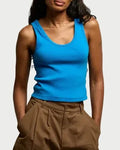 Woman wearing a blue tank top and brown shorts against a plain background