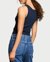 Woman wearing a navy top and blue jeans against a beige backdrop