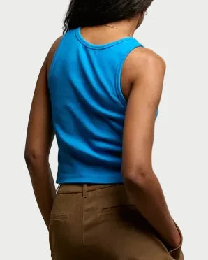 Person wearing a blue sleeveless top and brown shorts against a neutral background