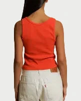 Person wearing a red top and white pants standing against a plain background