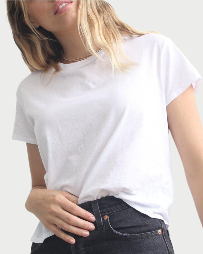 A woman with blonde hair wears the perfectwhitetee Harley Boxy Crew in Black and White, styled with dark jeans against a light gray background. She stands casually with her hand on her hip, face partially out of frame.