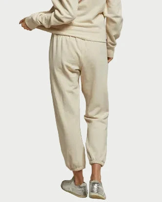 Model wears a cream Perfectwhitetee Johnny Sweatpant in Sugar and matching French terry cotton sweatshirt, seen from the back with silver sneakers against a plain white background.