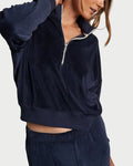 Woman wearing a navy tracksuit against a plain background