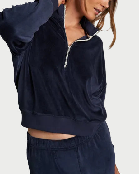 Woman wearing a navy tracksuit against a plain background