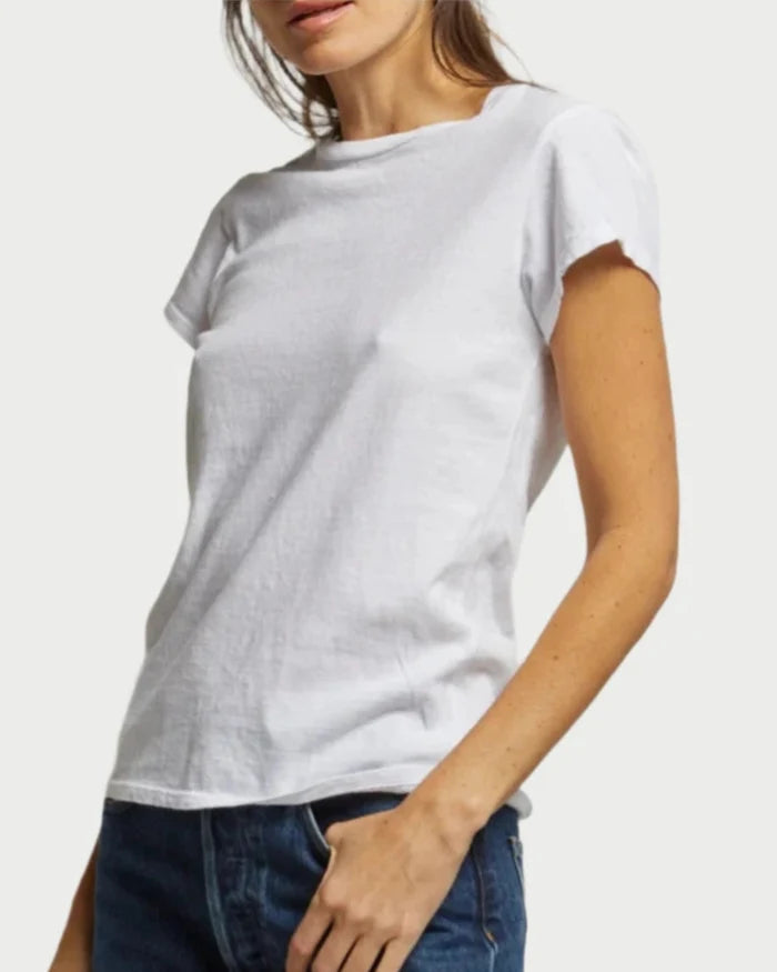 A woman stands against a light background wearing the Sheryl Basic Tee by perfectwhitetee and blue jeans. Her face is partially out of frame, and one hand rests on her hip.