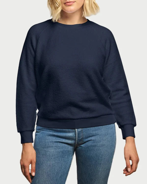 A person wearing a perfectwhitetee Ziggy Sweatshirt in navy with long sleeves and light blue jeans, standing against a light gray background.