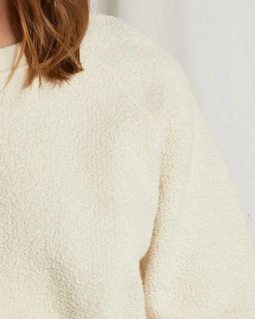 Close-up of a textured beige sweater with a blurred background