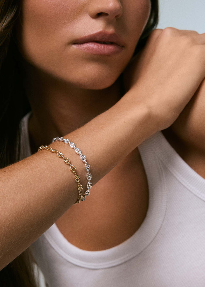 woman in a white tank top wearing a Kinn 925 Sterling Silver Petite Puffed Mariner Chain Bracelet stacked with a 14k Gold Petite Puffed Mariner Bracelet
