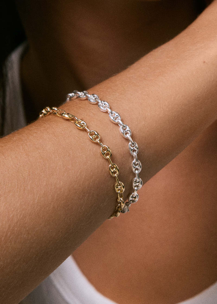 close up of a woman's arm wearing a Kinn 925 Sterling Silver Petite Puffed Mariner Chain Bracelet stacked with a 14k Gold Petite Puffed Mariner Bracelet