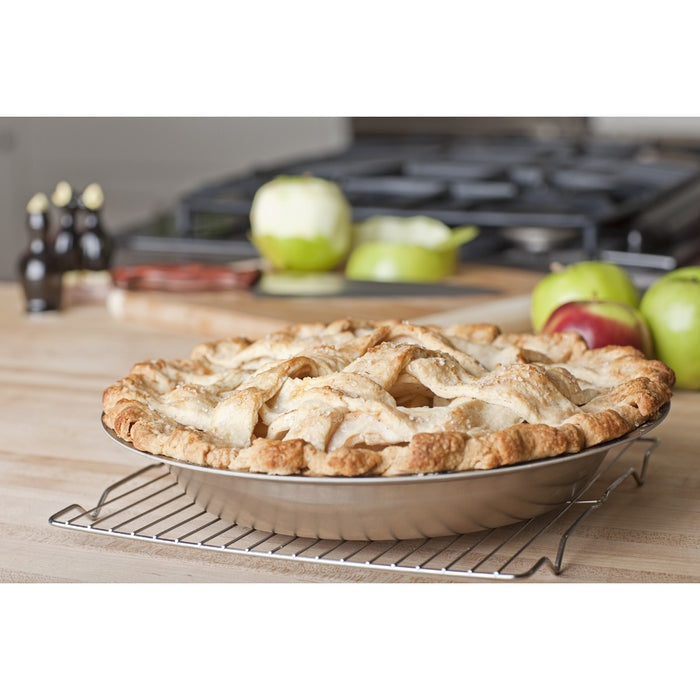 Side view of stainless steel pie pan with lattice-top apple pie, showing fluted rim and polished finish on wire rack