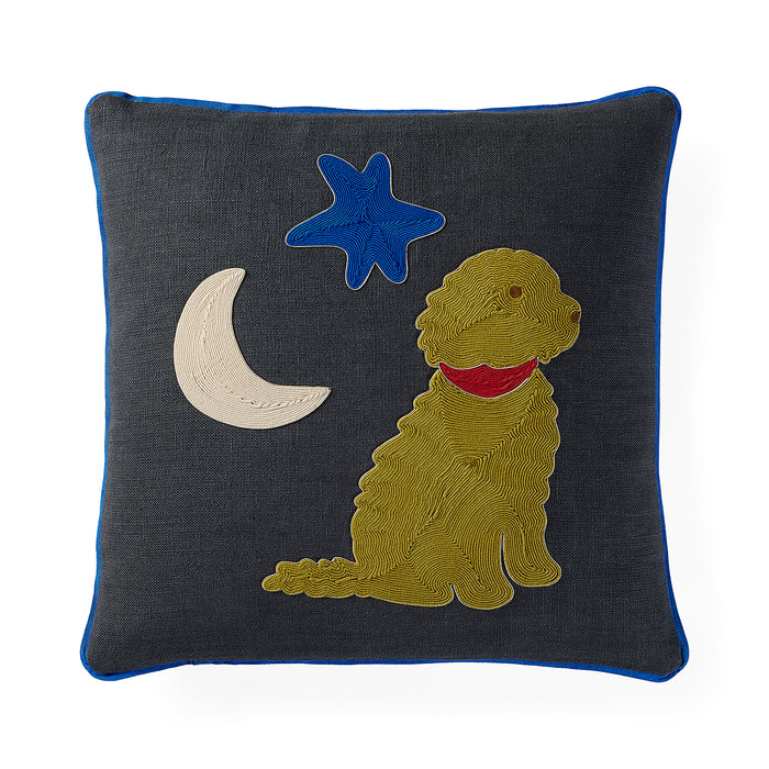 A square dark gray throw pillow with a blue piped edge, featuring an embroidered design of a golden dog wearing a red collar, a blue star, and a cream crescent moon.