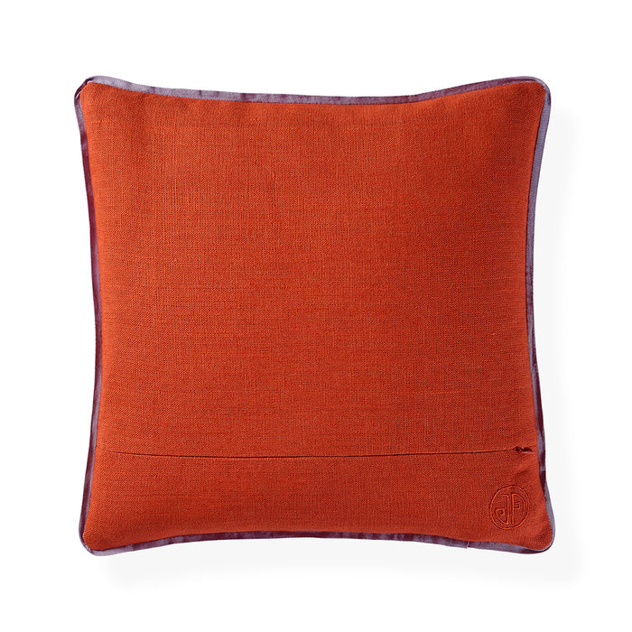 A square orange-brown textured throw pillow with a dark purple border trim and a small embroidered monogram logo in the bottom right corner, shown on a white background.