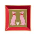 A square decorative plate with a red border, gold trim, and a central olive-green panel featuring two pink dogs wearing red bows, set against a plain white background.