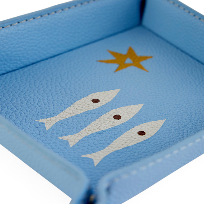 Blue leather tray with gold star and white fish designs on a white background