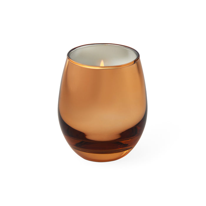 An amber glass candle holder with a lit candle inside, set against a plain white background.