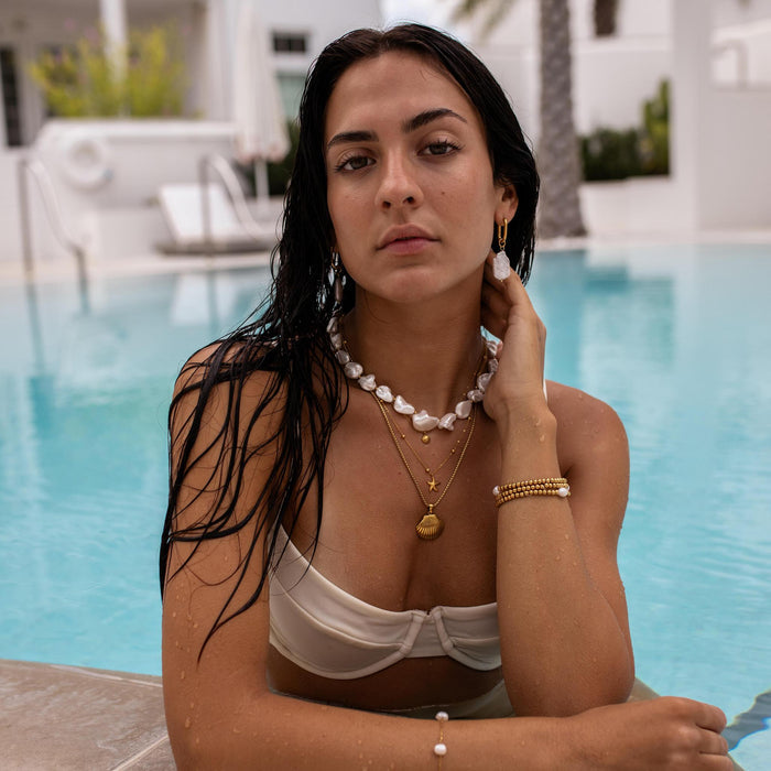 a woman in a pool on vacation wearing pearl and gold jewelry by ALCO Jewelry