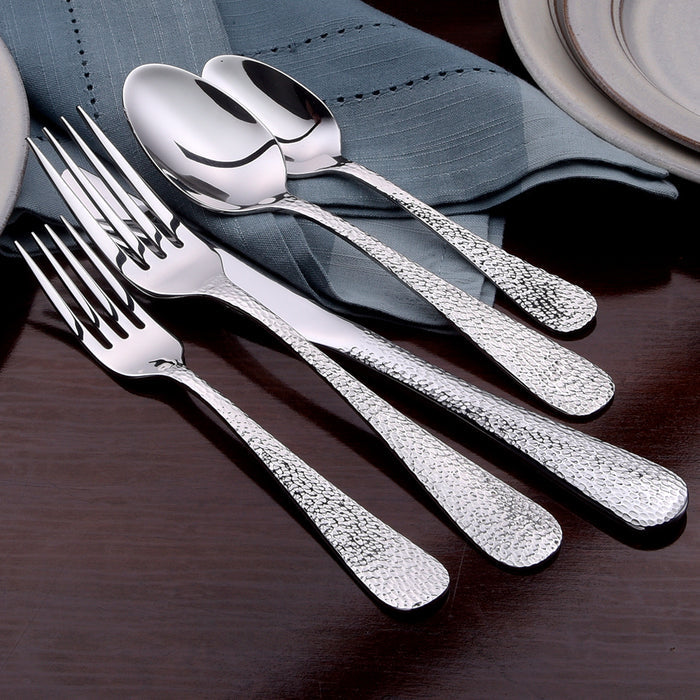 Close-up of Providence 45-piece set showing hammered teardrop textured handles on dark wood table with blue napkin