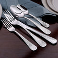 Close-up of Providence 45-piece set showing hammered teardrop textured handles on dark wood table with blue napkin