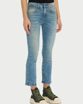 Person wearing light blue jeans and green sneakers on a white background